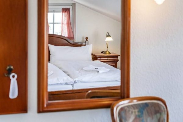 Double bed in an attic-style room at Hotel Stranddistel – book accommodation with balcony in Goehren, Ruegen Island