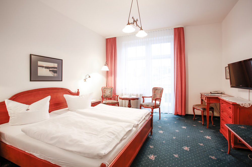 Schlafzimmer des Doppelzimmers mit Balkon im Hotel Stranddistel auf der Insel Rügen